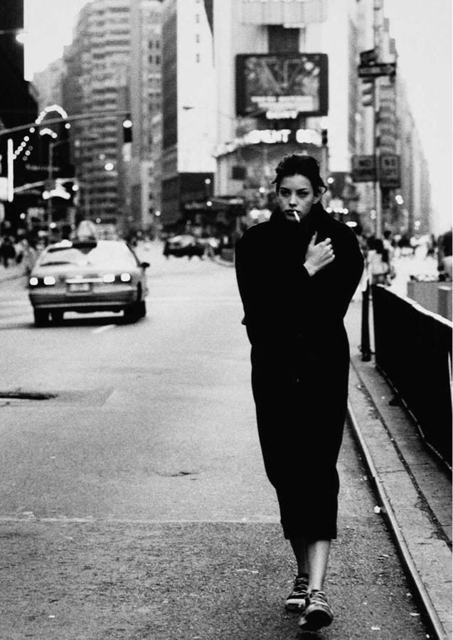 Woman in long coat walking through New York at dusk