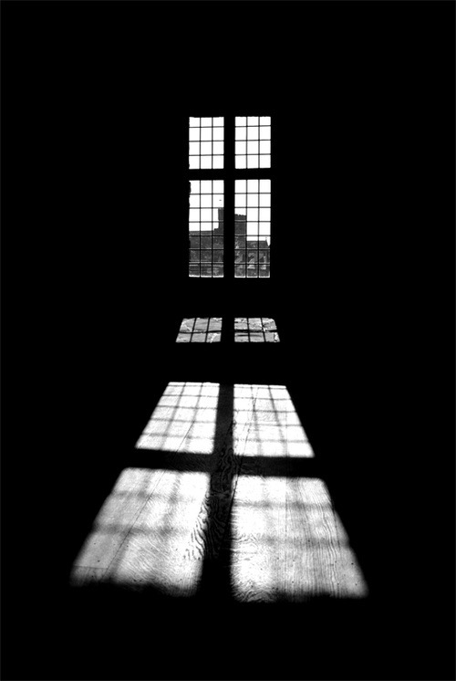 Window light projected onto floorboards in a dark room