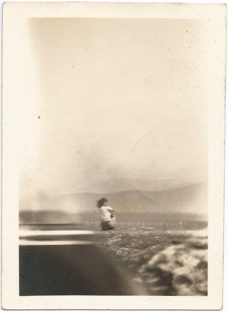 A faded vintage snapshot of a figure by a lake